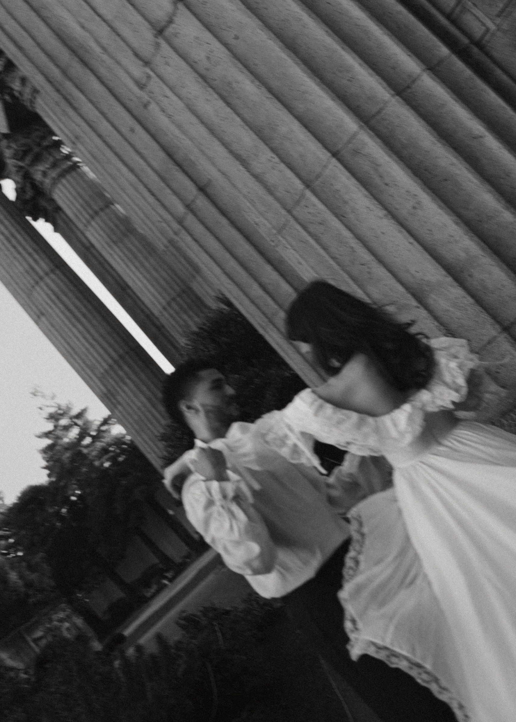 A tilted black-and-white portrait of Berkeley and Robin beneath the Palace of Fine Arts columns