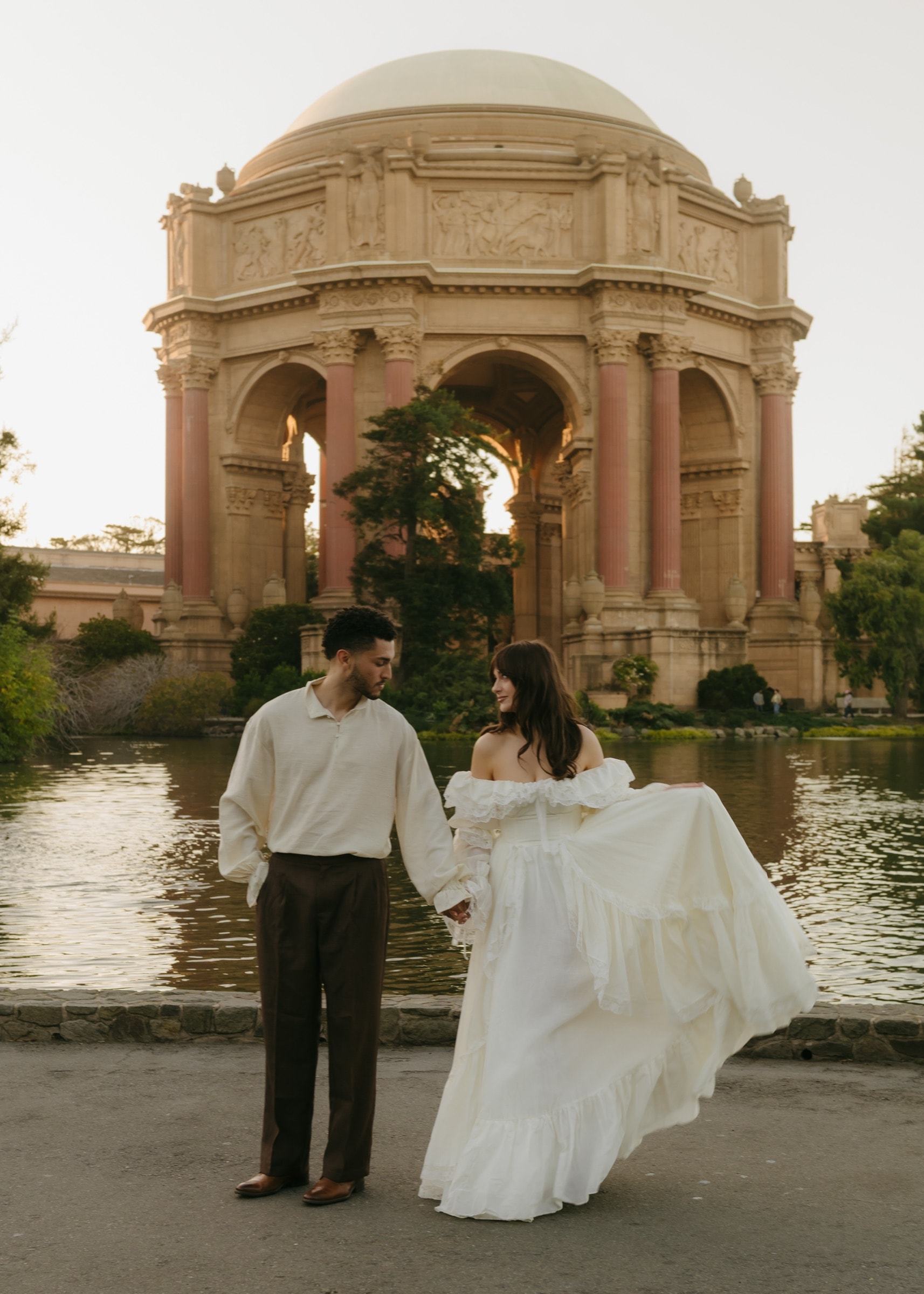Berkeley and Robin walking hand in hand by the lagoon before the Palace of Fine Arts rotunda