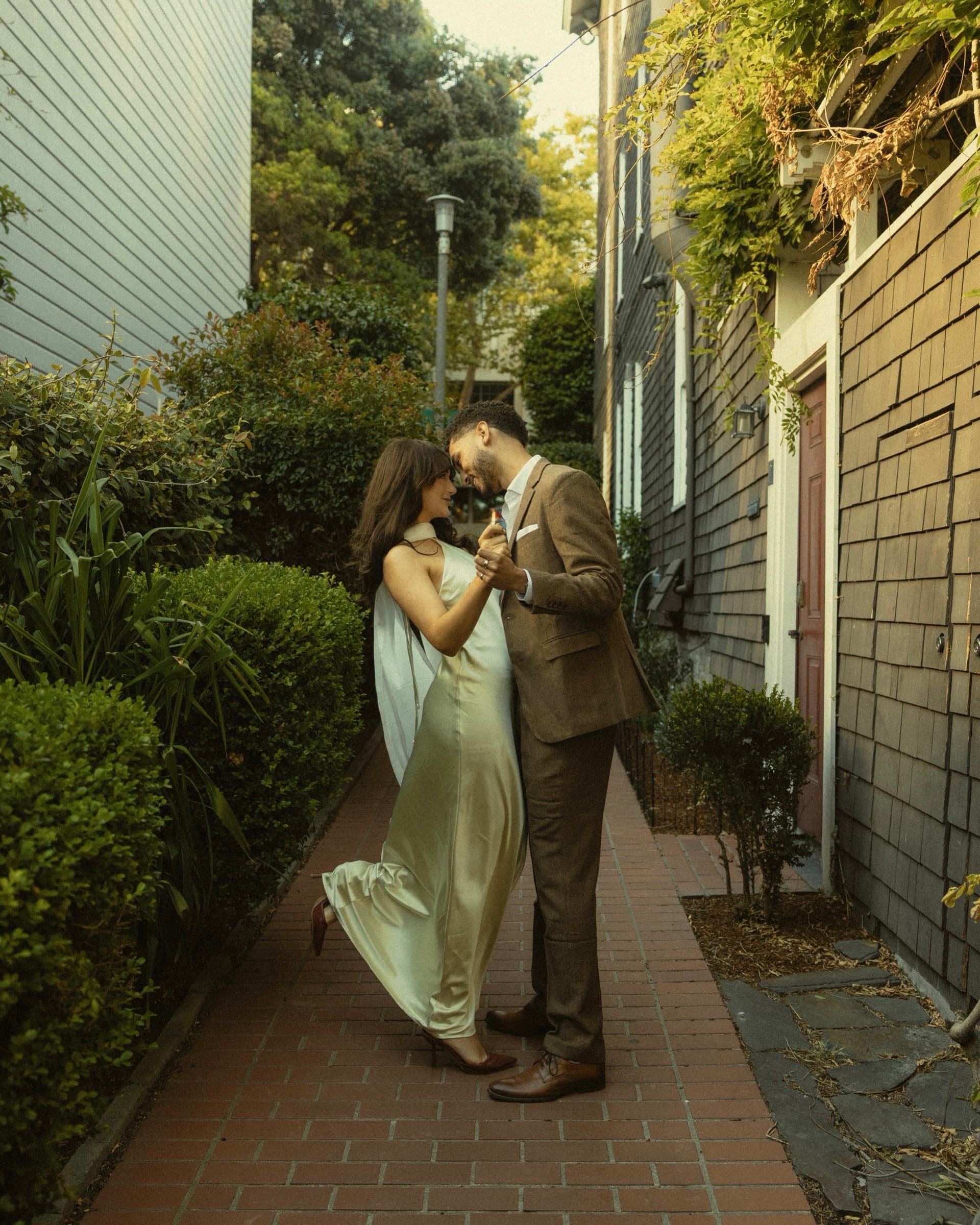 Berkeley and Robin dancing in a shingled alleyway lit by a lantern